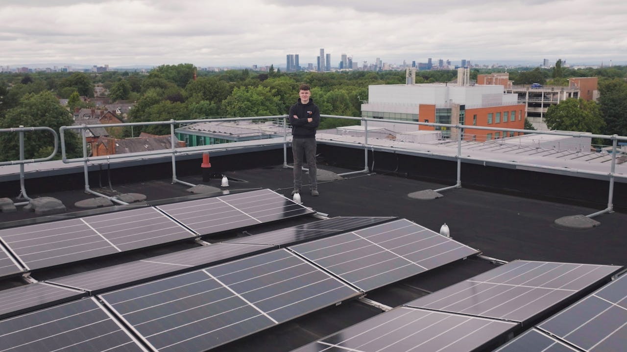Home Person on a rooftop with solar panels showcasing renewable energy and technology.