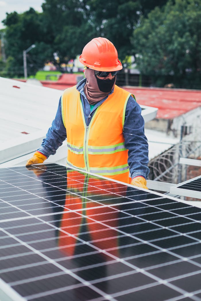 Home Technician in protective gear installing solar panels on a sunny day.