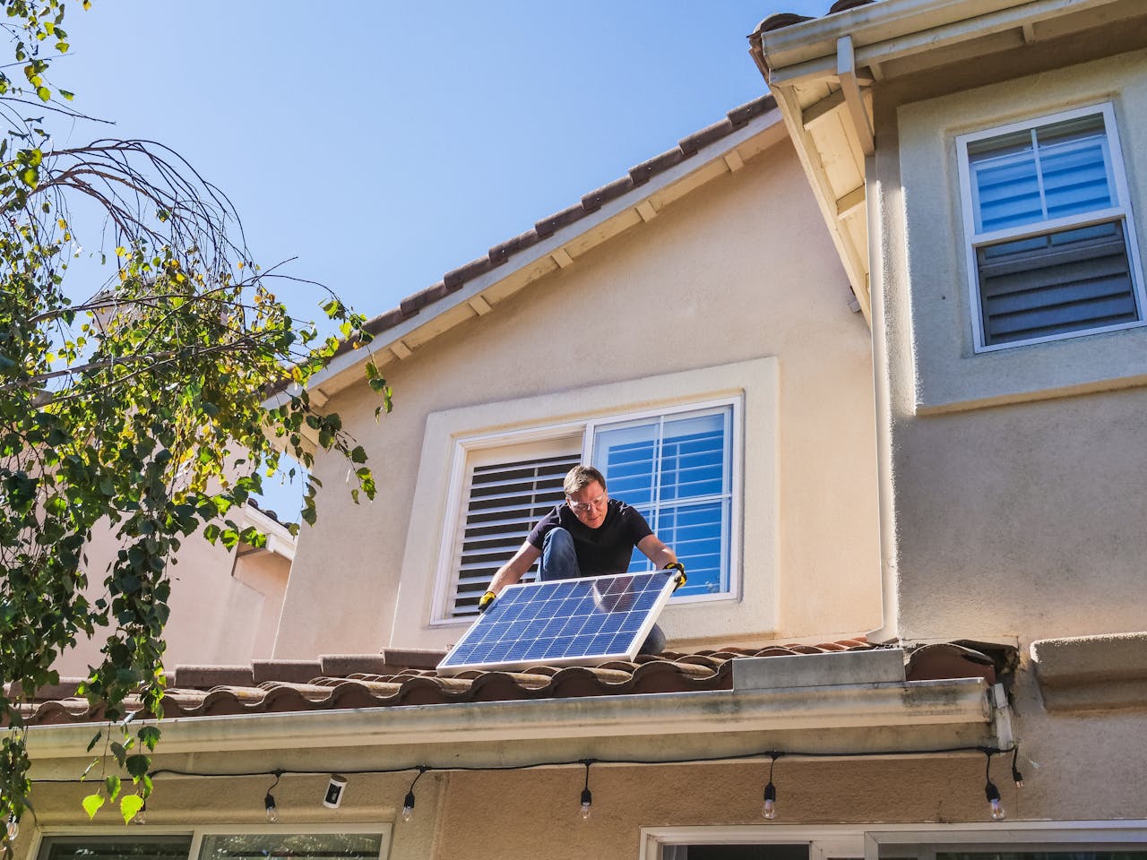 Solar technician installing photovoltaic panels on a sunny rooftop.
